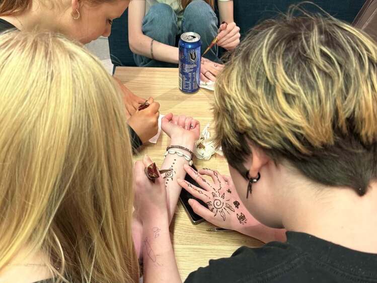 students applying henna designs on hands and arms