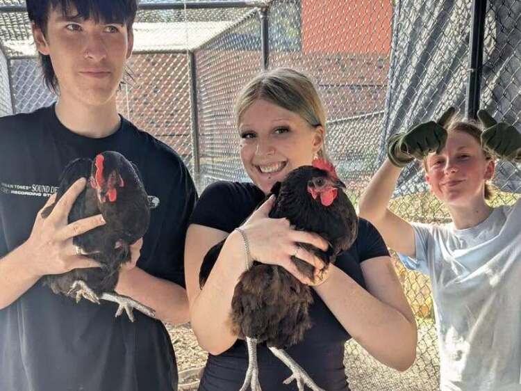 2 students smiling holding chickens