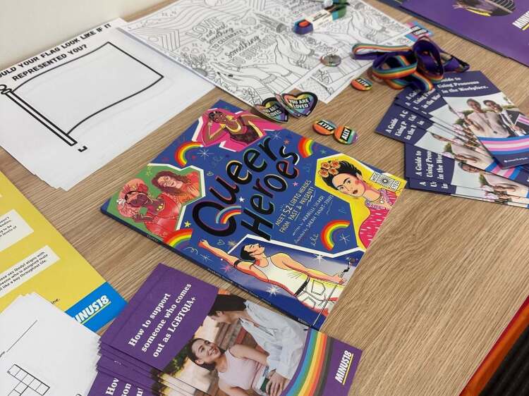 Queer Heroes book and support flyers for pride month, including ally badges and ranbow lanyards