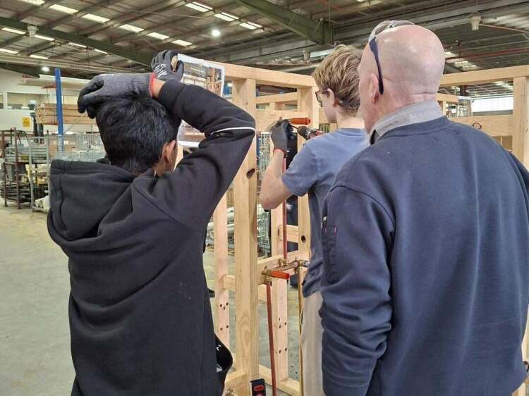 Students constructing a wooden frame being supervised by adult at Swinburne