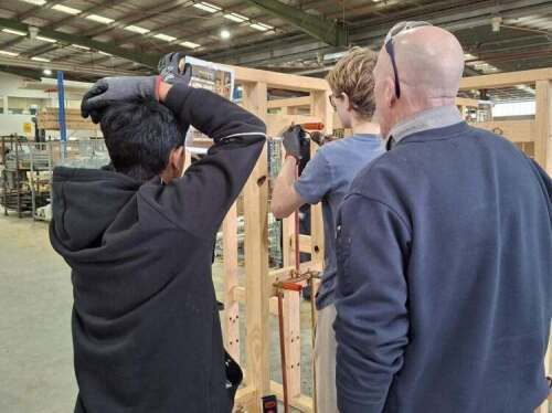 Students constructing a wooden frame being supervised by adult at Swinburne