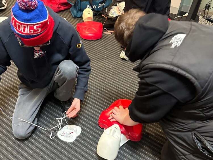 2 male students practising CPR on dummy