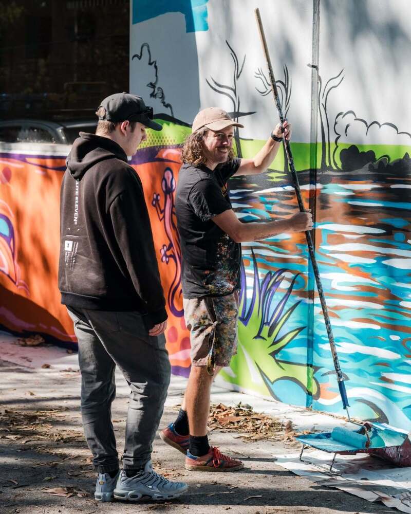 artist painting mural with large paint roller