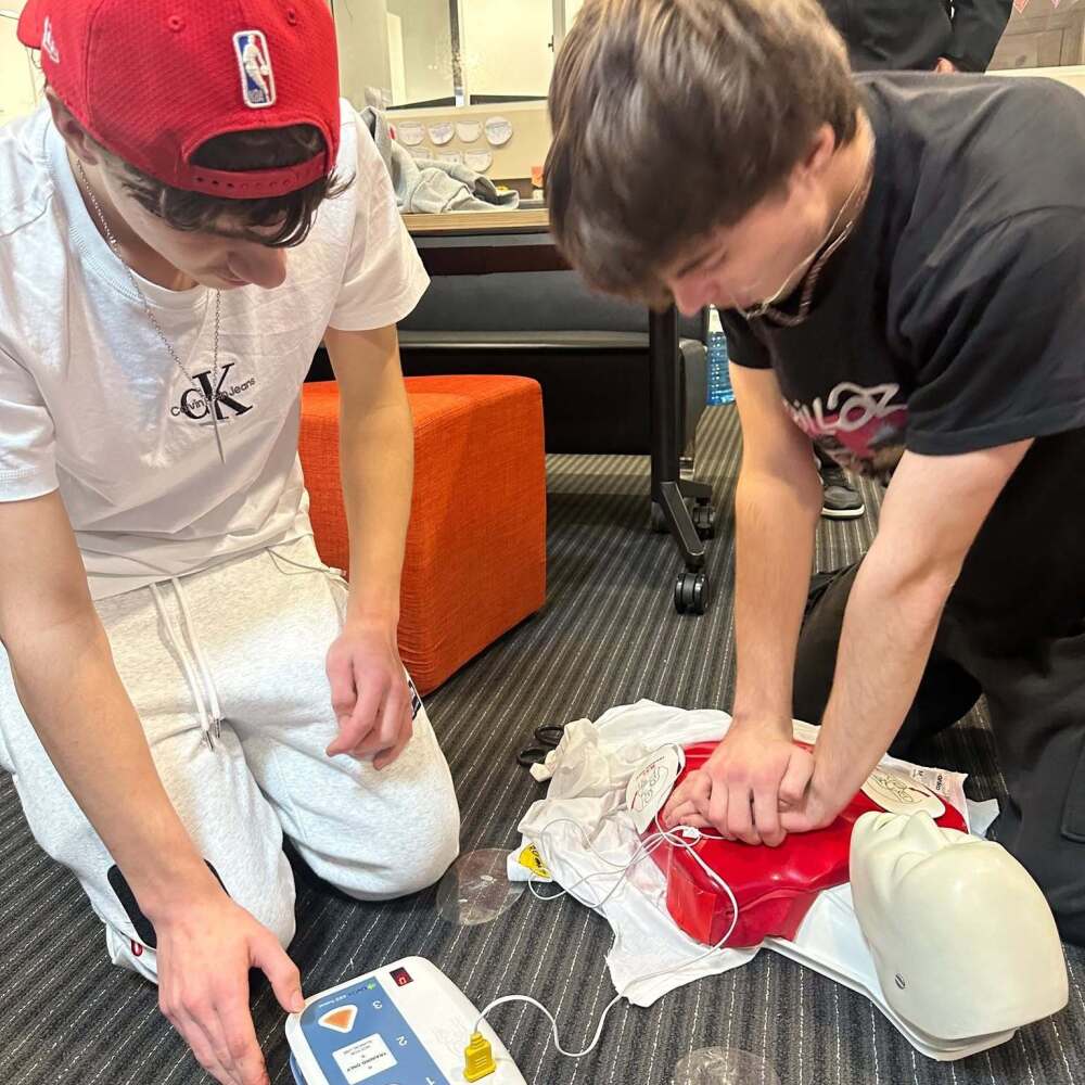 2 male students practising chest compressions on a dummy