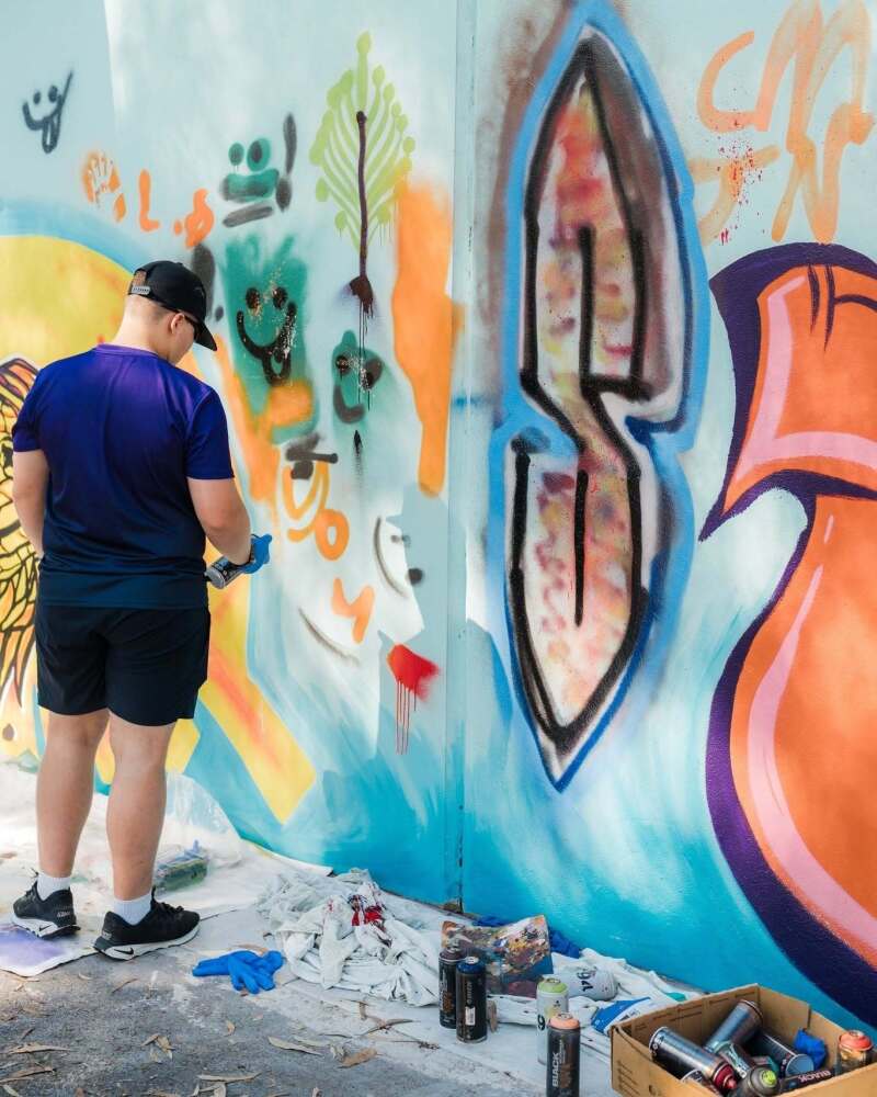 student assisting with mural painting using paint spray can