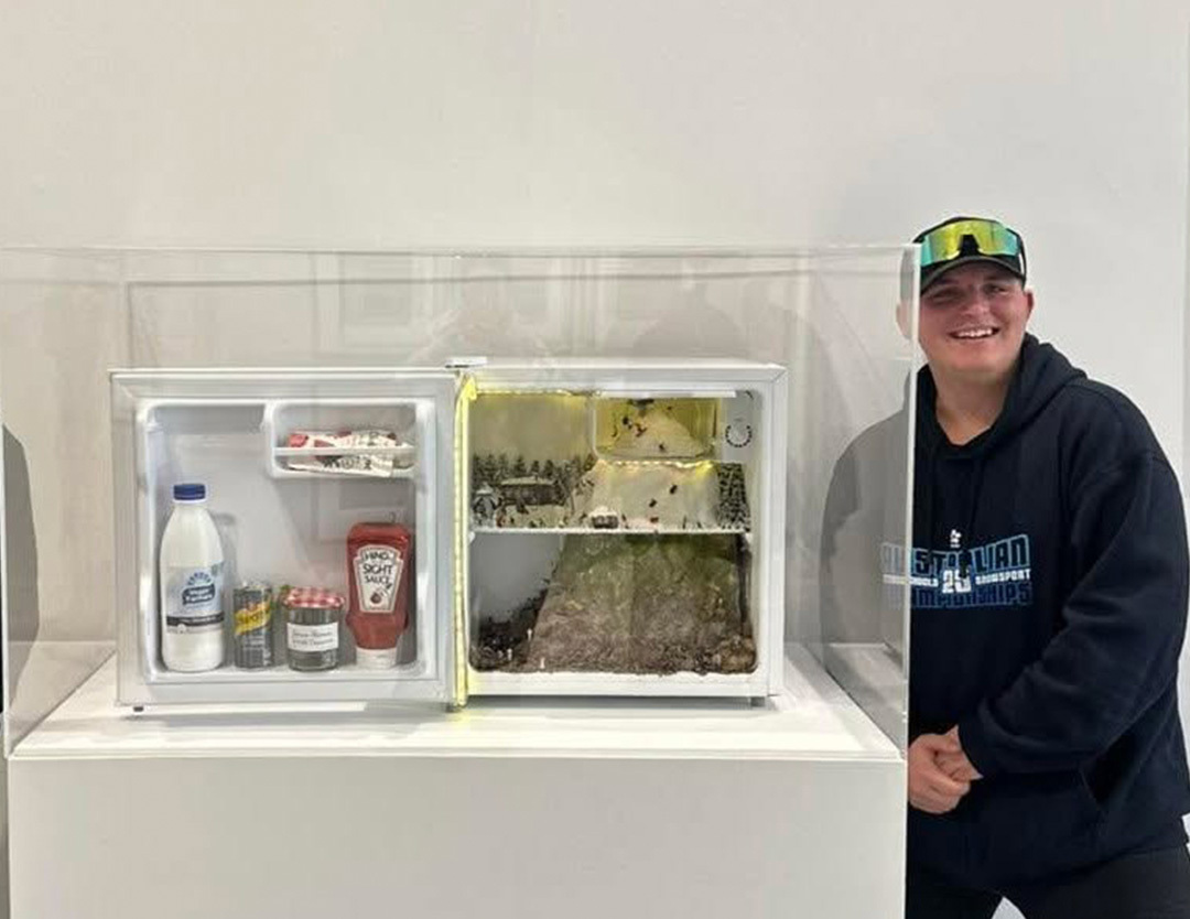 student smiling next to artist modern sculpture