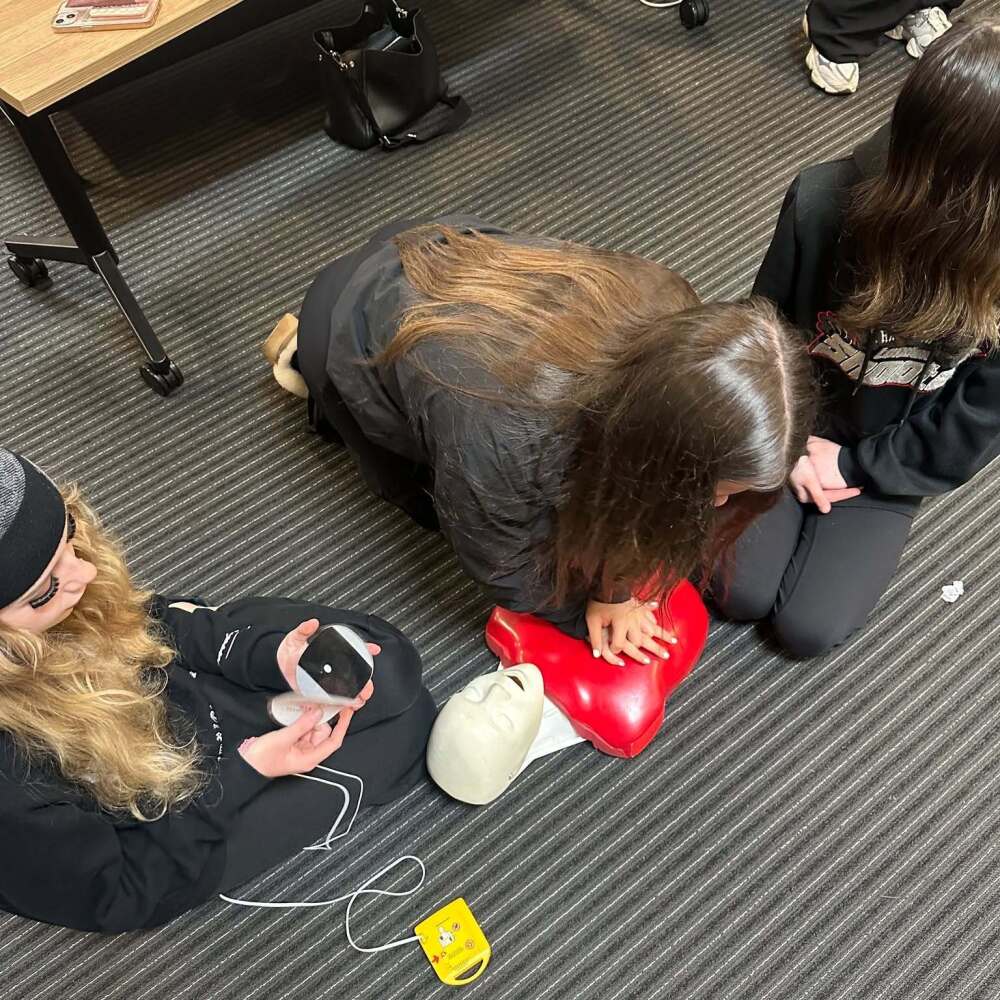 3 female students practising chest compressions on a dummy