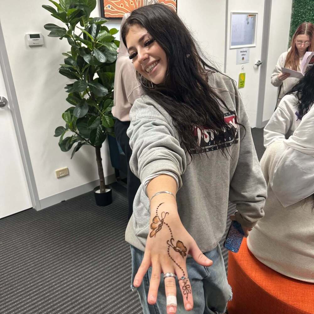 student showing off her butterfly henna design on her hand 