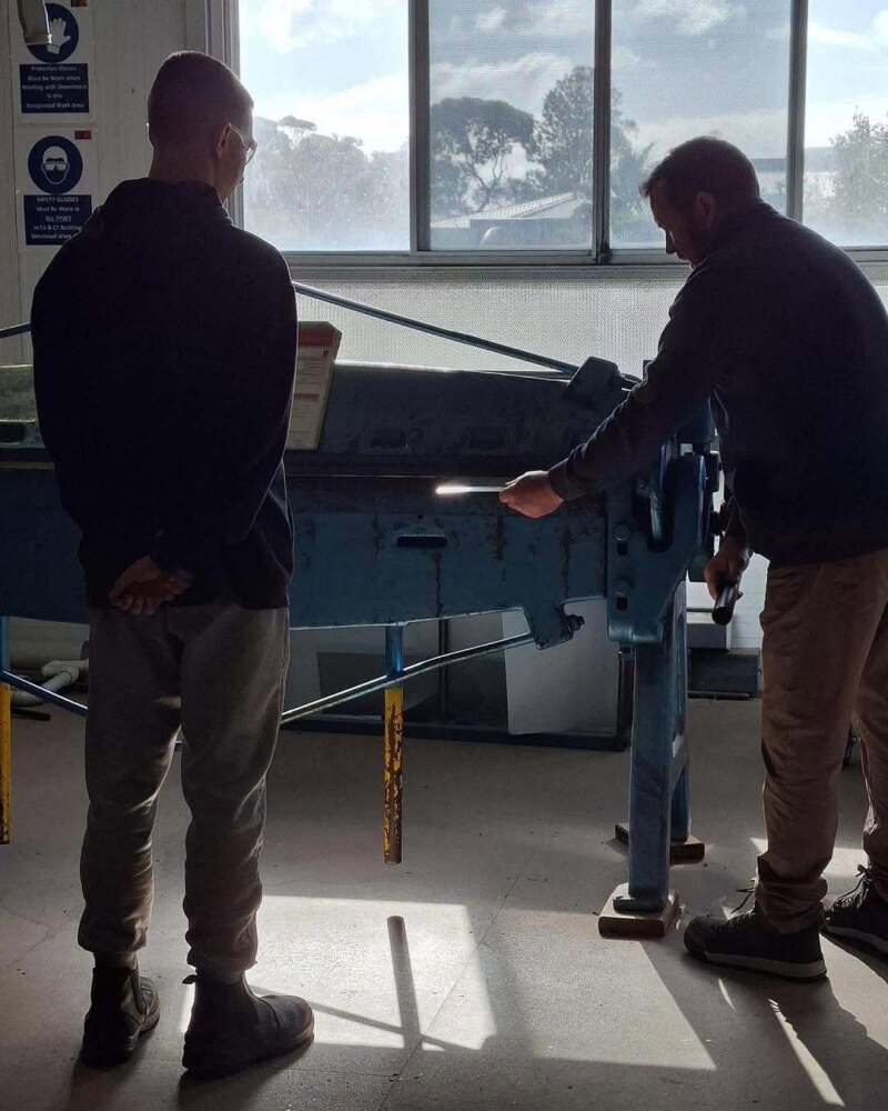 Teachers demonstrating trade using machine