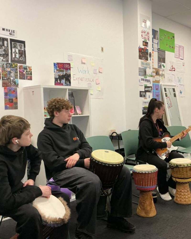 Urban College students participating in a guided music session with drums and guitar
