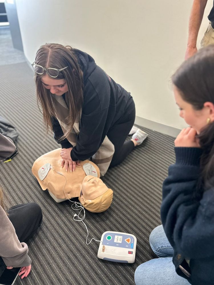 student doing CPR on first aid dummy
