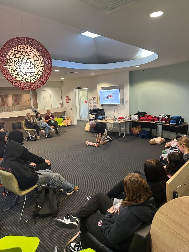 instructor demonstrating first aid on dummy of baby in first aid class