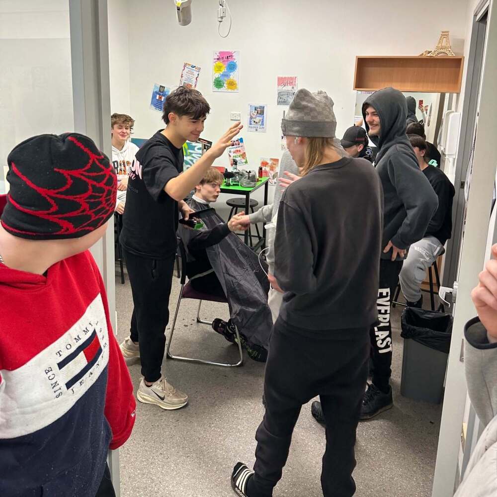 students supporting each other whilst getting haircuts