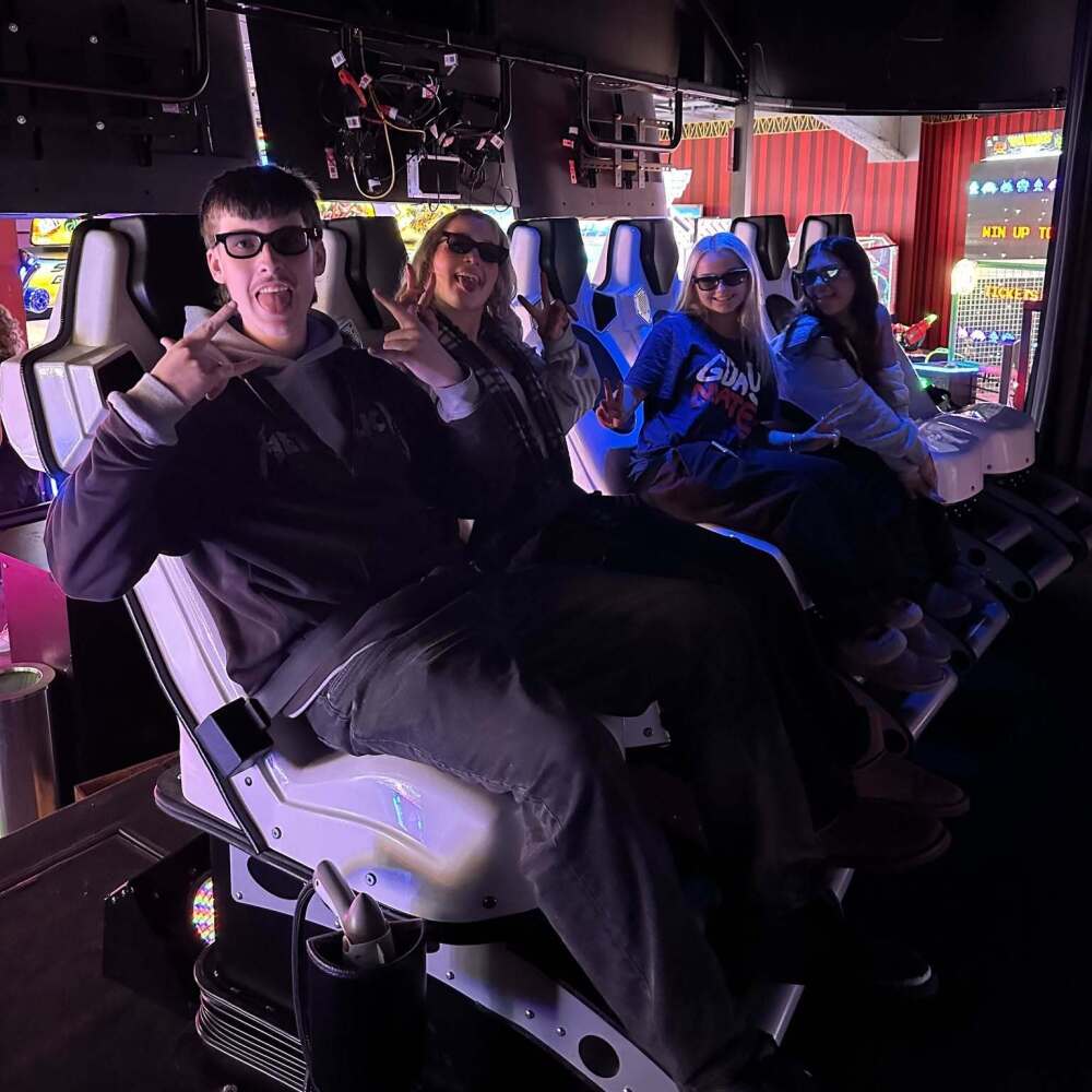 students sitting in chairs on exciting ride at the games arcade